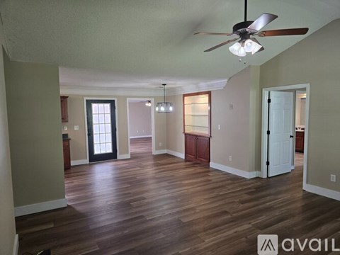 A spacious living room with wood flooring and a ceiling fan.