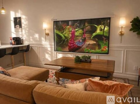 A living room with a large painting on the wall and a coffee table in the center.