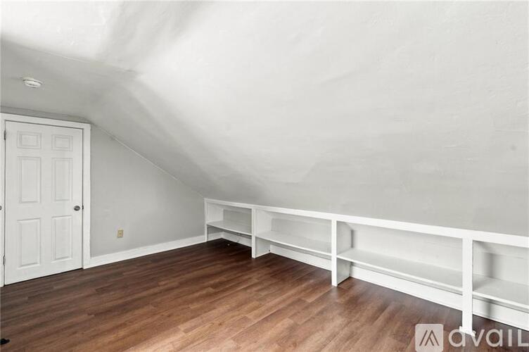A white room with a wooden floor and a white door.