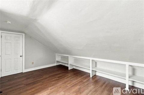 A white room with a wooden floor and a white door.