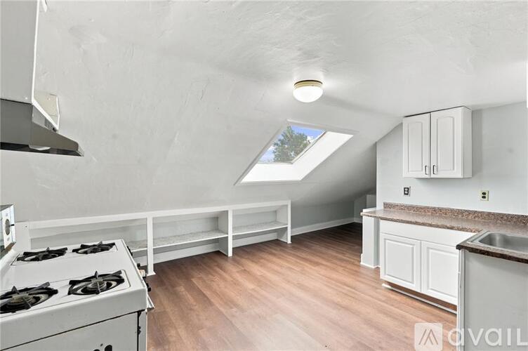 A kitchen with a stove top oven and a skylight.