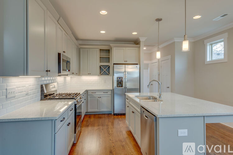 A modern kitchen with stainless steel appliances and wooden floors.