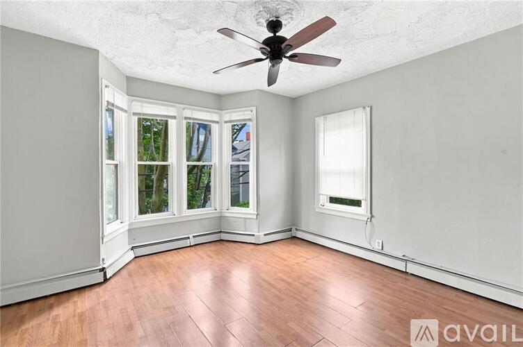 A room with a ceiling fan and a window with a view of trees.