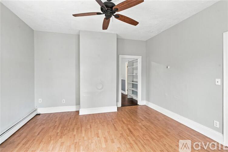 A room with a ceiling fan and wooden flooring.