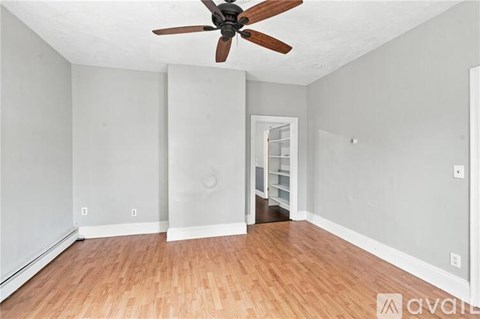 A room with a ceiling fan and wooden flooring.