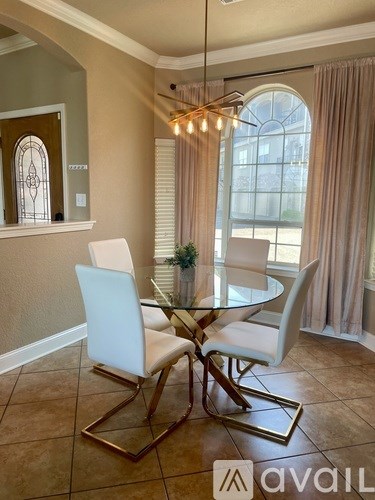 A dining room with a glass table and white chairs.