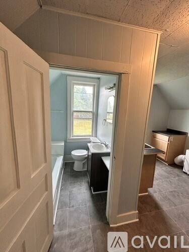 A bathroom with a toilet, sink, and window.