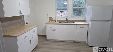 A kitchen with white cabinets and a wooden countertop.