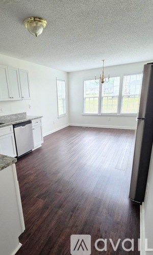 A kitchen with white cabinets and a black refrigerator.