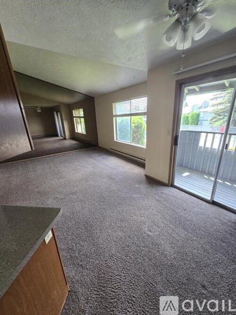 A room with a ceiling fan and sliding glass doors.