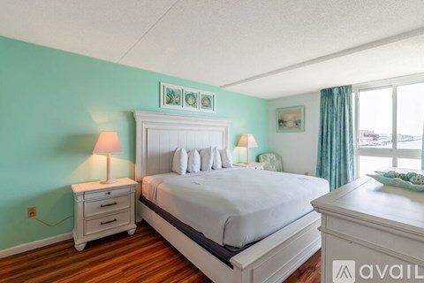 A bedroom with a large bed, a nightstand with a lamp, and a dresser.