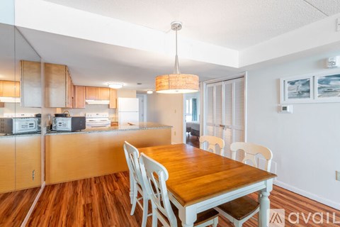 A kitchen with a table and chairs in the foreground and a counter with appliances on it in the background.