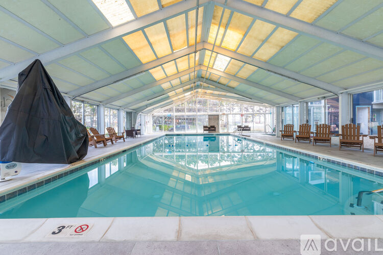 A large indoor swimming pool with a black tarp covering some lounge chairs.
