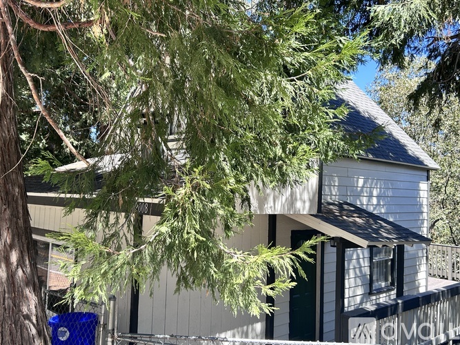 A house with a blue trash can in front of it.