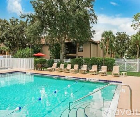 A swimming pool with lounge chairs and trees in the background.