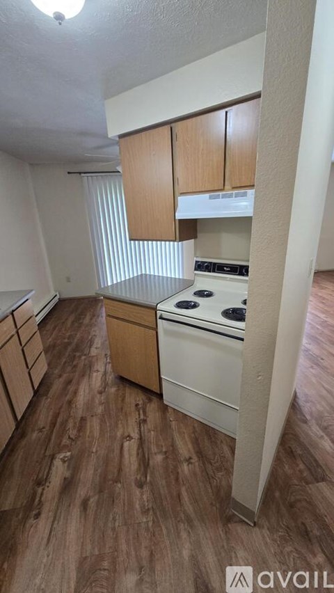 A kitchen with wooden floors and white appliances.
