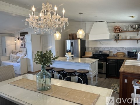 A kitchen with a table and chairs in the foreground and a chandelier hanging from the ceiling.