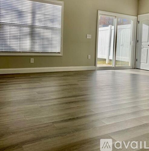 A room with wooden flooring and a window with blinds.