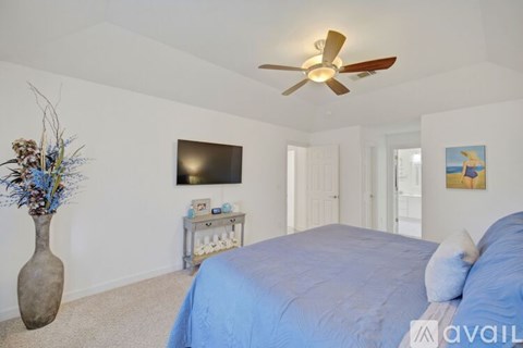 A bedroom with a blue bed and a ceiling fan.