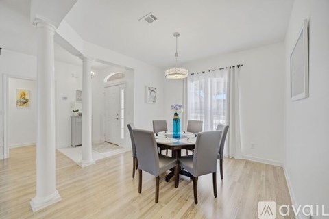 A dining room with a table set for two and a chandelier hanging from the ceiling.