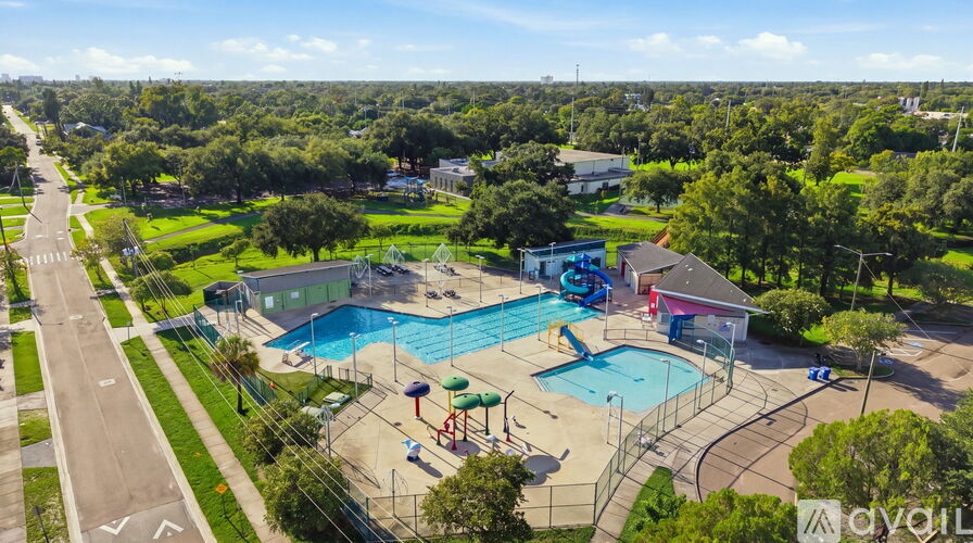 A large outdoor swimming pool surrounded by a fence and a playground.