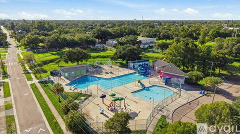 A large outdoor swimming pool surrounded by a fence and a playground.