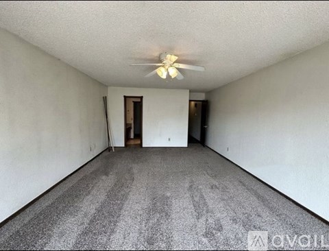 A spacious room with a ceiling fan and carpeted floor.