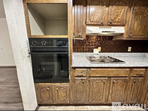 A kitchen with wooden cabinets and a black oven.