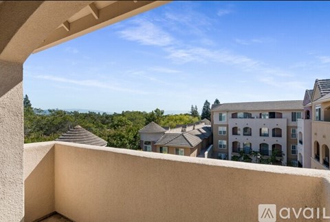 A view from a balcony overlooking a residential area with houses and trees.