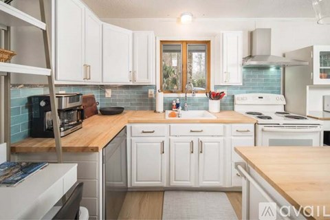 A kitchen with white cabinets and a wooden countertop.