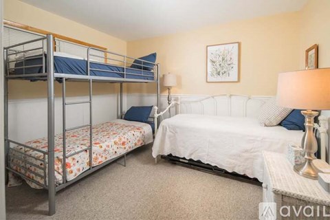 A bedroom with a bunk bed and a single bed with pillows and a lamp.