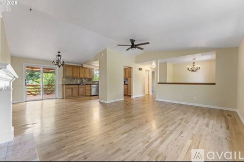 A spacious room with wooden floors and a ceiling fan.