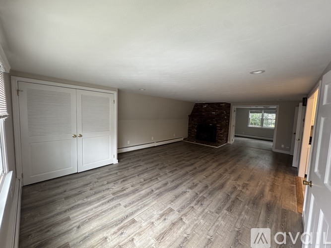 A room with wooden flooring and a fireplace.