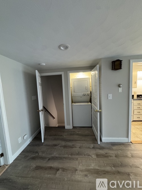 A room with a grey floor and white walls, with a doorway leading to another room.