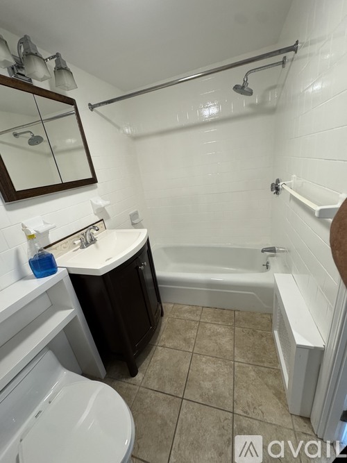 A bathroom with a white tub, a white toilet, a sink, and a mirror.