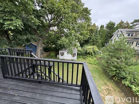 A deck with a railing overlooking a green yard.