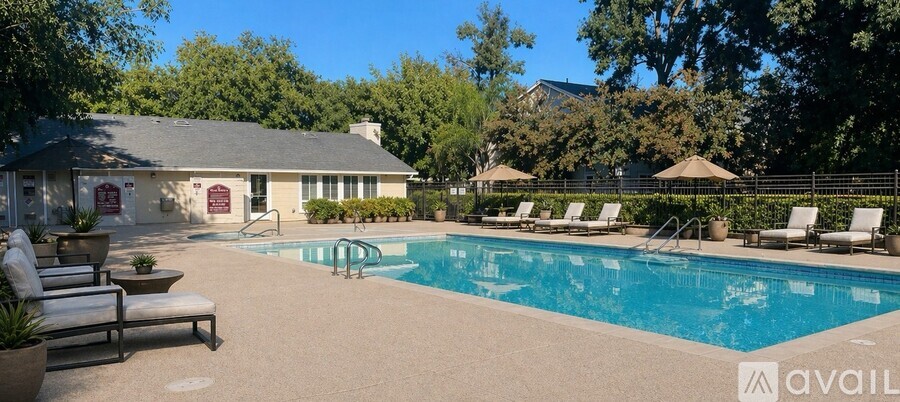 A pool with lounge chairs and a house in the background.