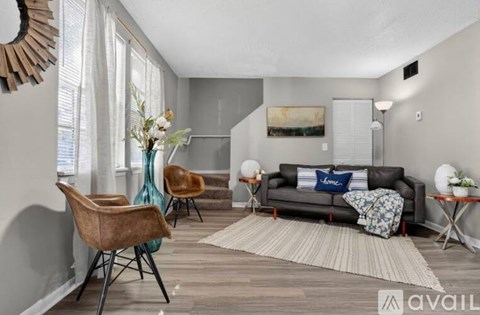 A living room with a grey couch, a brown chair, and a painting on the wall.