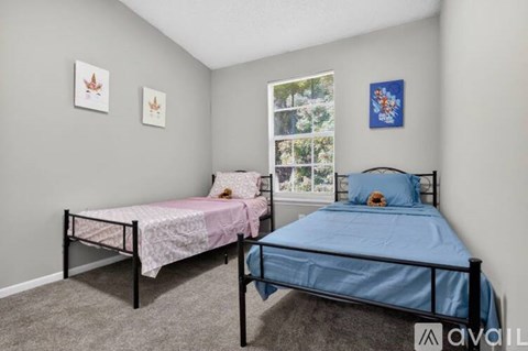 A bedroom with two beds, one with a pink bedspread and the other with a blue bedspread.