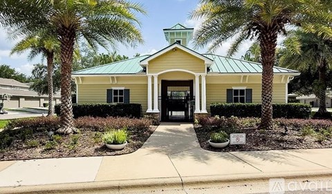 A yellow building with a green roof is surrounded by palm trees.
