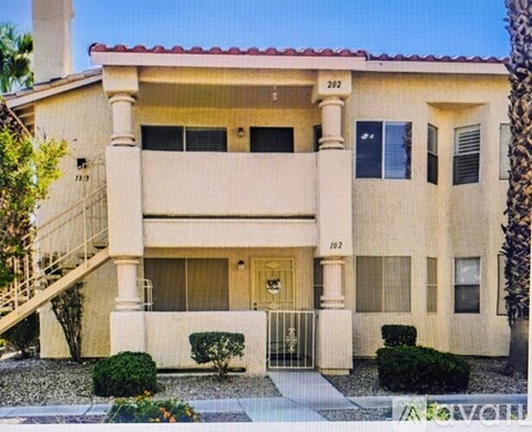 A beige house with a red tile roof and a balcony on the second floor.