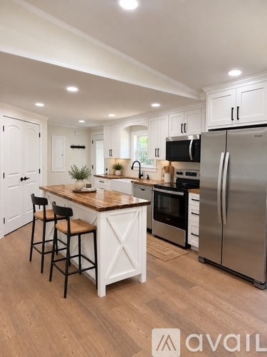 A kitchen with white cabinets and a wooden island.