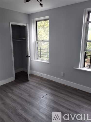 A room with a grey floor and a window with a view of trees outside.