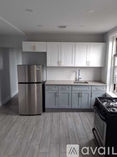 A kitchen with a stainless steel refrigerator and a black stove top oven.
