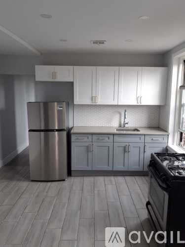 A kitchen with a stainless steel refrigerator and a black stove top oven.
