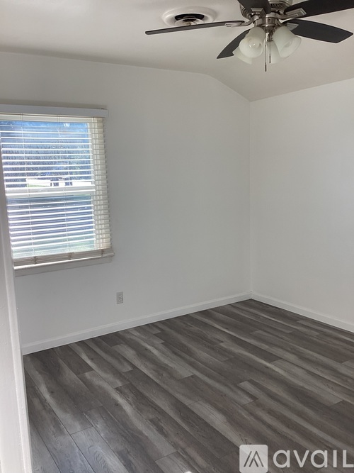 A room with a ceiling fan and a window with blinds.