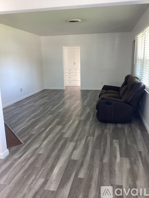 A living room with a brown couch and wooden flooring.