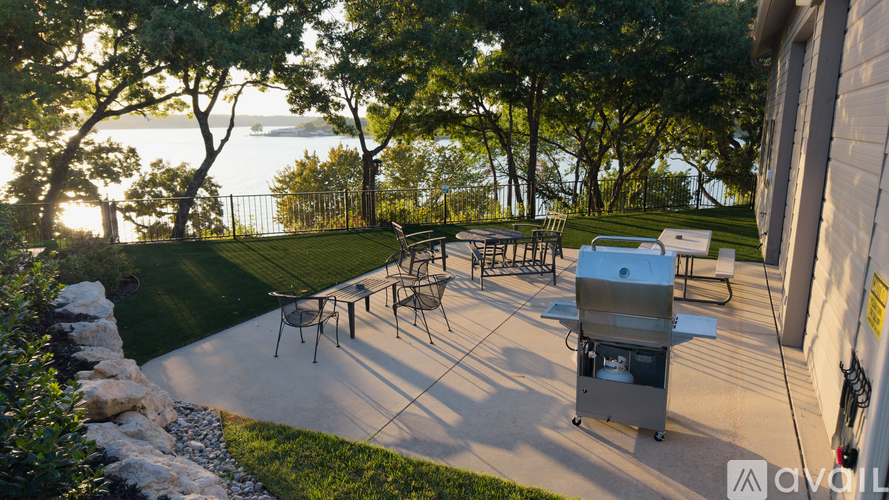 A BBQ grill is set up on a patio with a view of the water.