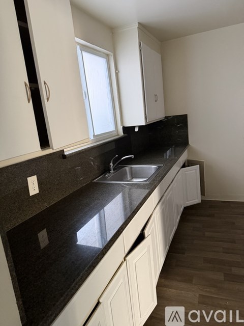 A kitchen with white cabinets and a black countertop.
