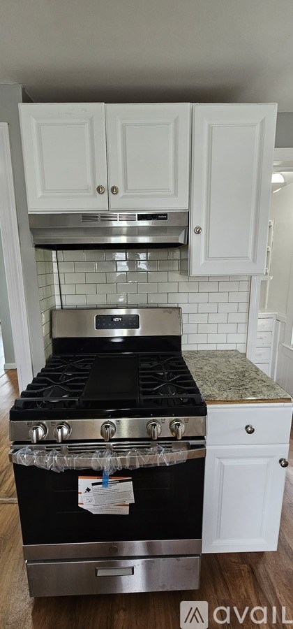 A kitchen with a black stove top oven and white cabinets.